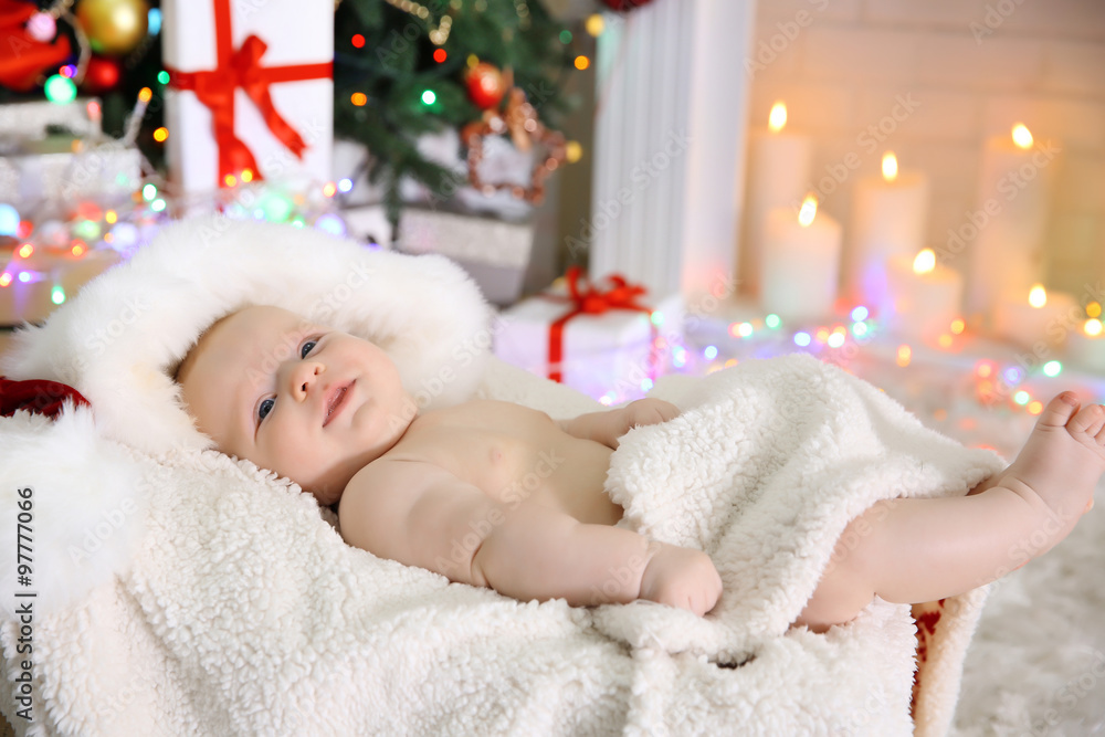 Obraz premium Cute naked baby in red hat on the warm blanket, close up