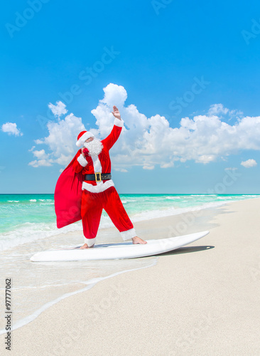 Photography Santa Claus windsurfer on surfboard with Christmas bag at beach