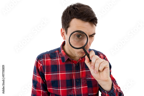 Surprised Young man student holding magnifying glass looking to something isolated over white background.