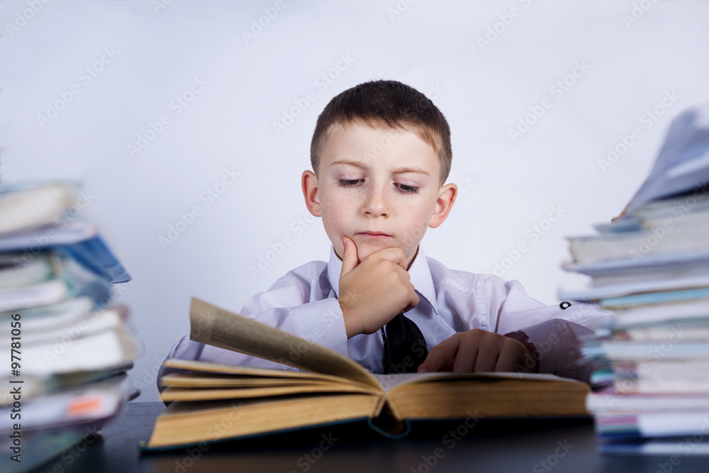 Little child thinking leaning on pile of books, isolated grey background.Thoughtfully child with a stack of books leaning on them.Education concept Little child thinking leaning on pile of books, isolated grey background.Thoughtfully child with a stack of books leaning on them.Education concept