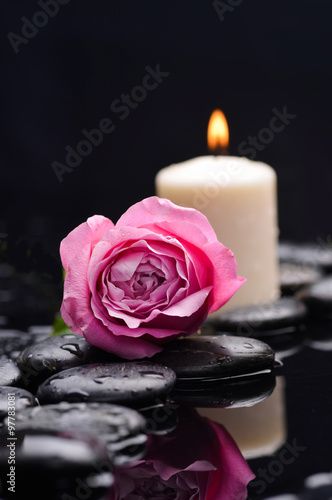 Beautiful rose with candle and therapy stones 