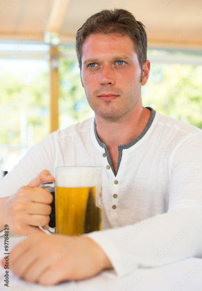 Handsome man with beer in summer cafe. Handsome man with beer in summer cafe.