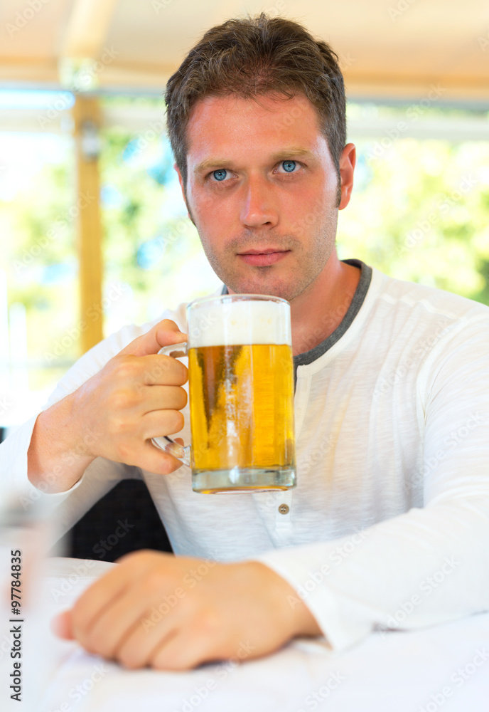 Handsome man with beer in summer cafe. Handsome man with beer in summer cafe.