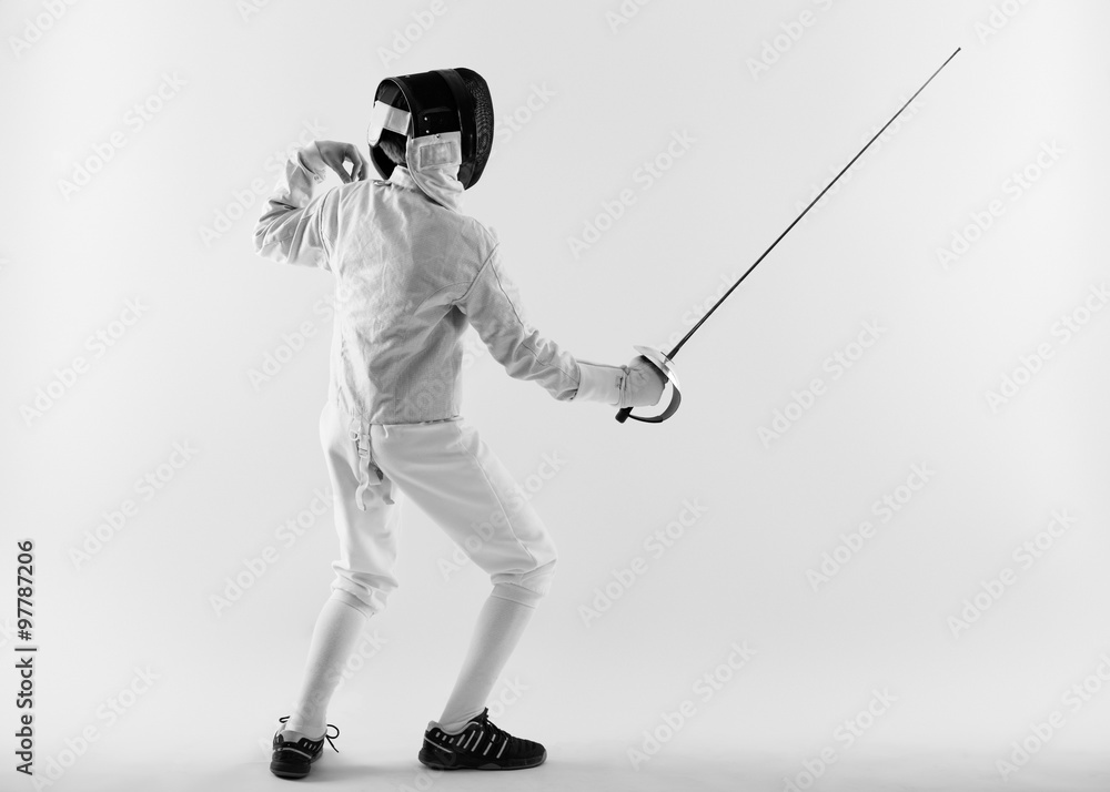 Boy wearing white fencing costume and black fencing mask standing with