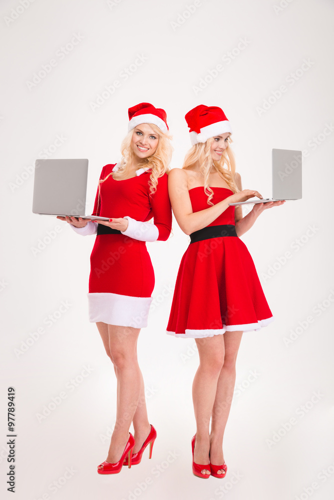 Two smiling women in santa cloth using laptop computer Two smiling women in santa cloth using laptop computer