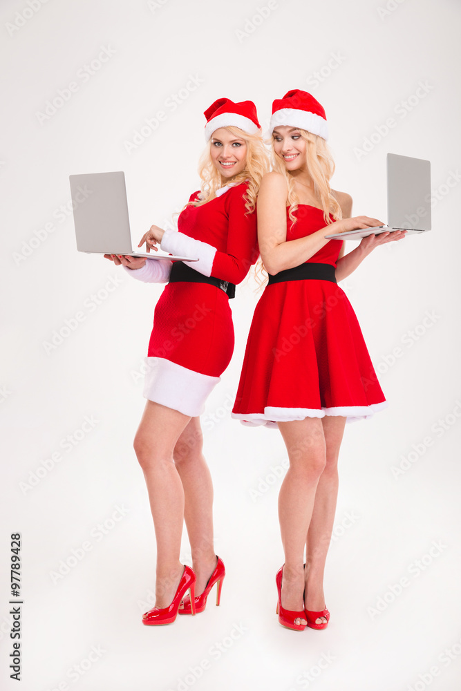 Two happy women in santa cloth using laptop computer