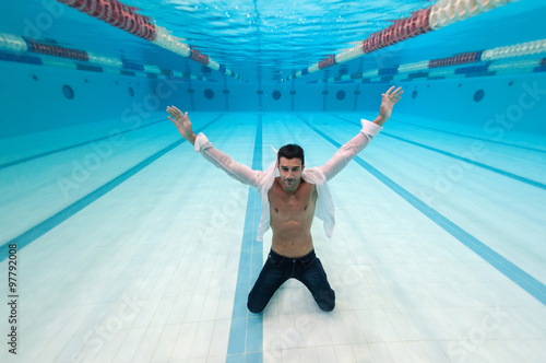 Man portrait wearing white shirt inside swimming pool. Underwater image. © pio3