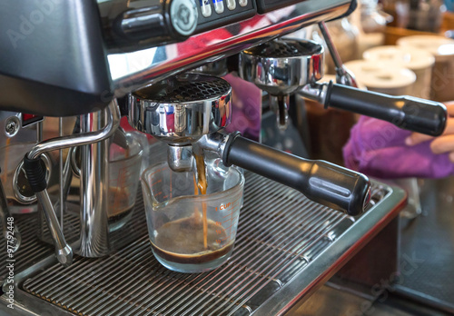 Close up coffee machine preparing fresh coffee and pouring into cup.