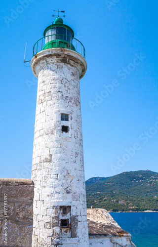 White stone lighthouse tower with green top