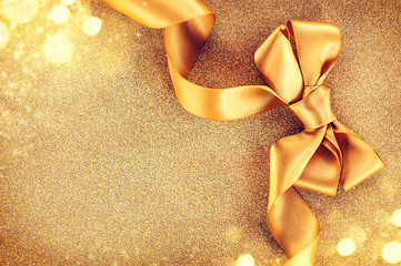 Christmas golden satin ribbon bow on a blinking holiday background