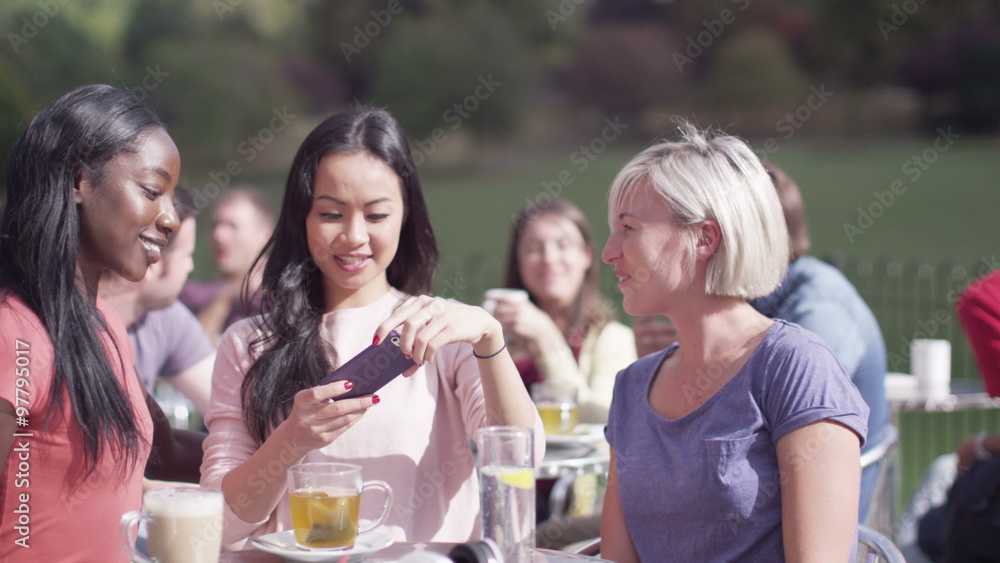 Happy attractive young female friends pose to take their own photo at outdoor cafe Happy attractive young female friends pose to take their own photo at outdoor cafe