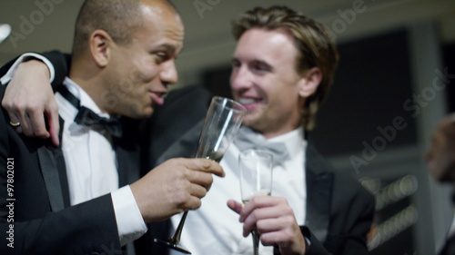 Male friends or business colleagues drinking and chatting at formal social event photo