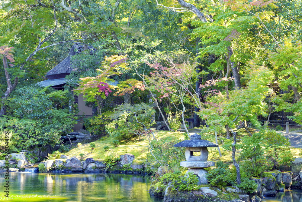 Japanese stone lantern in an autumn garden with colorful trees and lake Japanese stone lantern in an autumn garden with colorful trees and lake