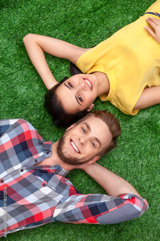 Young couple lying on green grass Young couple lying on green grass