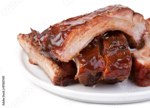 Barbecued Ribs Close-up – A plate of pork spareribs with barbecue sauce. On a white plate and white background.