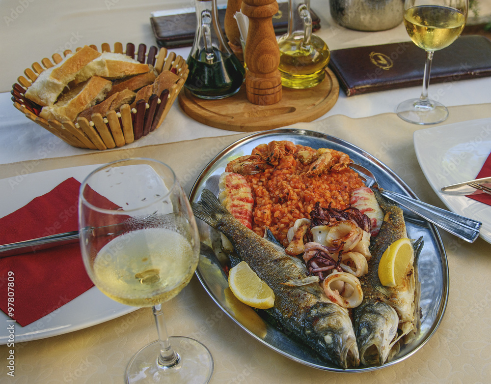 Grilled fish seabass. Meal for two with white wine glasses