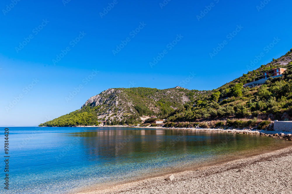 Beautiful azure blue Mediterranean beach surrounded by greenery