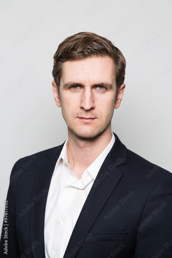 Blond-haired european businessman with a stern look stares into the camera while in front of a gradient background Blond-haired european businessman with a stern look stares into the camera while in front of a gradient background