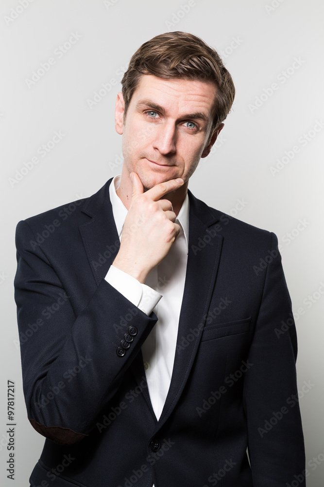 Blond-haired european businessman with a cheeky look stares into the camera while in front of a gradient background Blond-haired european businessman with a cheeky look stares into the camera while in front of a gradient background