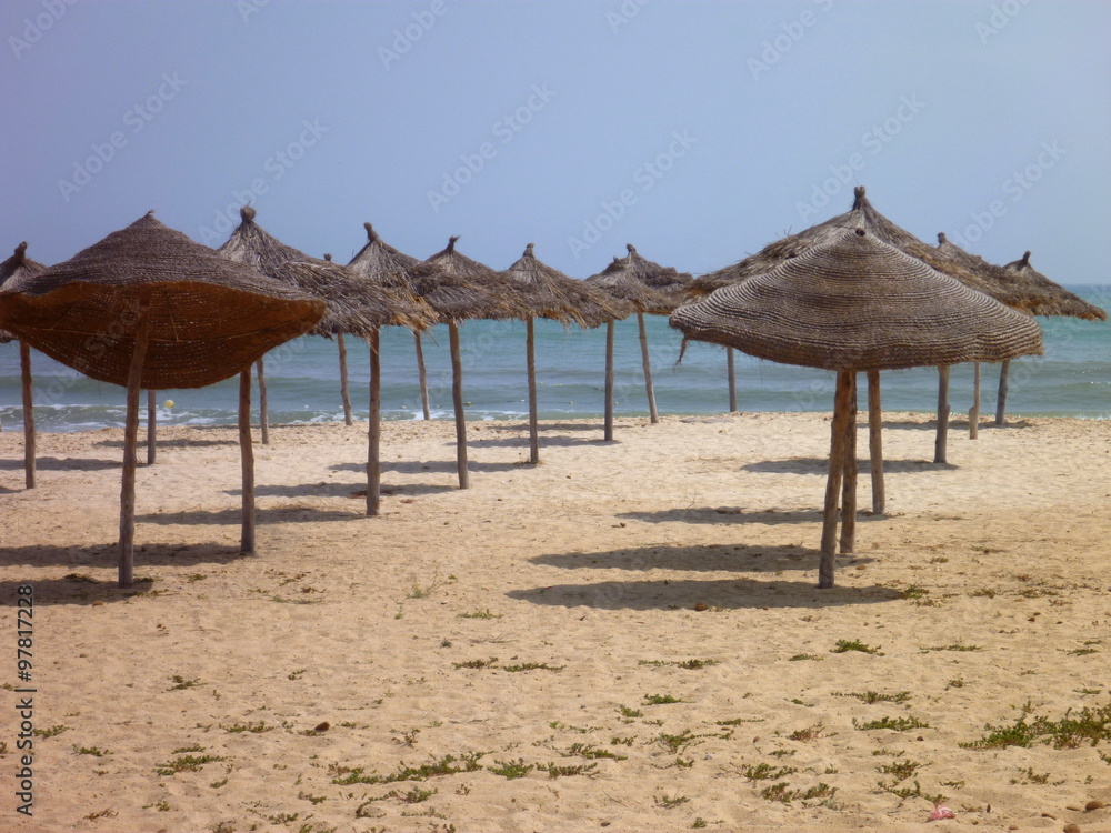 empty beach with straw umbrellas empty beach with straw umbrellas