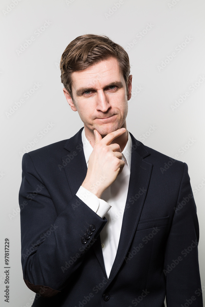 Blond-haired european businessman with a unconvinced look stares into the camera while in front of a gradient background Blond-haired european businessman with a unconvinced look stares into the camera while in front of a gradient background