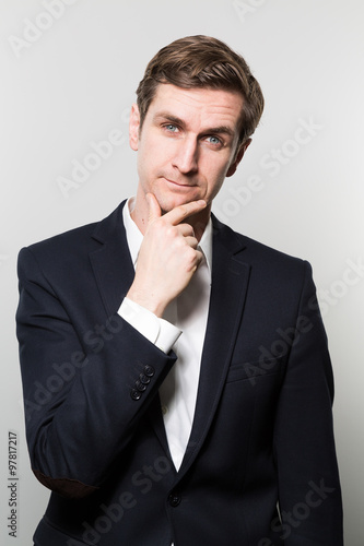 Blond-haired european businessman with a cheeky look stares into the camera while in front of a gradient background