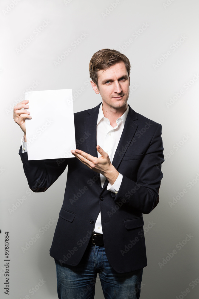 Blond-haired european businessman shows something on a piece of paper with a stern face while in front of a gradient background Blond-haired european businessman shows something on a piece of paper with a stern face while in front of a gradient background