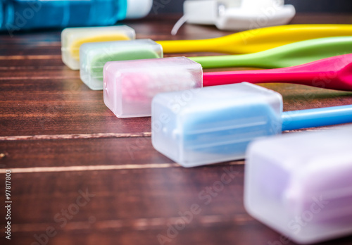 Set of colorful toothbrushs with mountwash and dental floss on wooden board photo