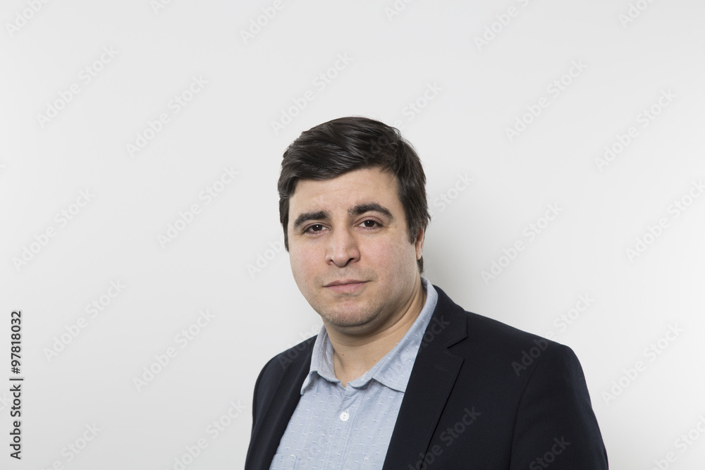 Dark haired man wearing blazer looking at camera. White background. Dark haired man wearing blazer looking at camera. White background.