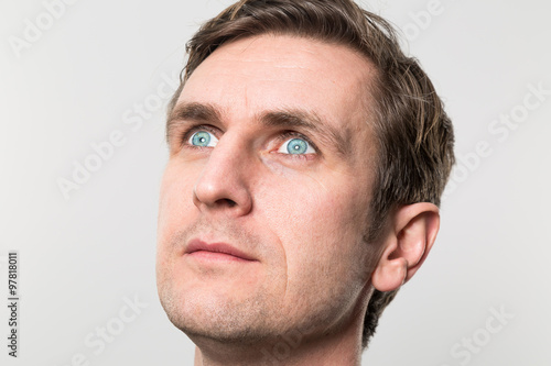 Even closer shot of a blond-haired european businessman with a pondering stare into the distance in front of a gradient background