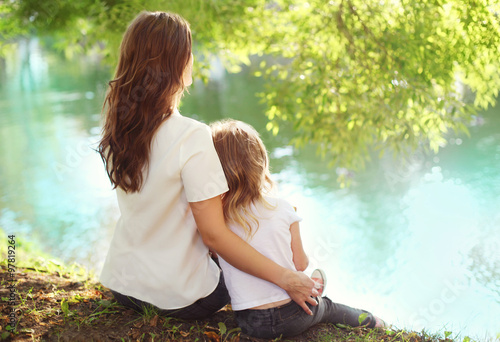 Happy mother and child daughter sitting together in summer day