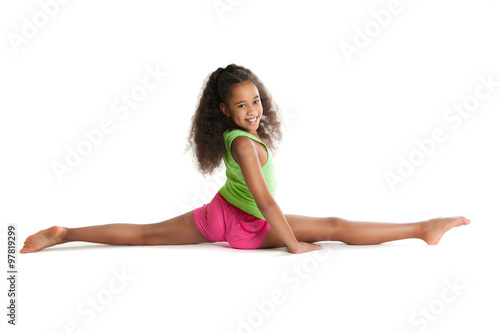 Slika na platnu Joyful dark-skinned girl sitting on the splits