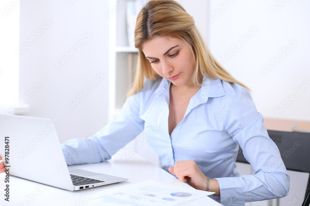 Portrait of young business woman sitting at the desk on office background Portrait of young business woman sitting at the desk on office background