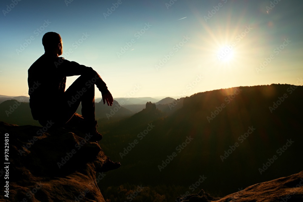 Hiker take relaxing on a rock and enjoying sunset at horizon. Vivid effect. Hiker take relaxing on a rock and enjoying sunset at horizon. Vivid effect.