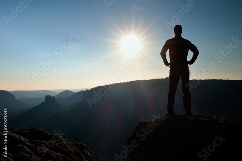 A man has his hands on  hips. Sportsman  silhouette in nature at daybreak.