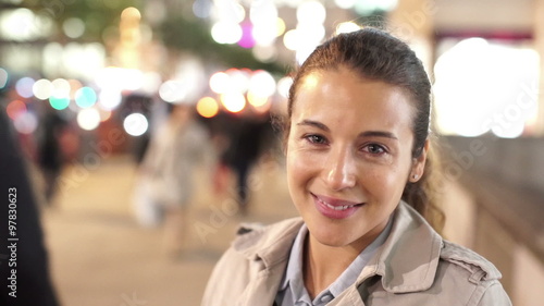 Portrait of smiling professional woman in city at night with crowds and traffic 