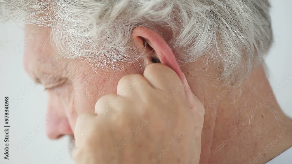 Senior man rubs his ear to relieve discomfort. Senior man rubs his ear to relieve discomfort.
