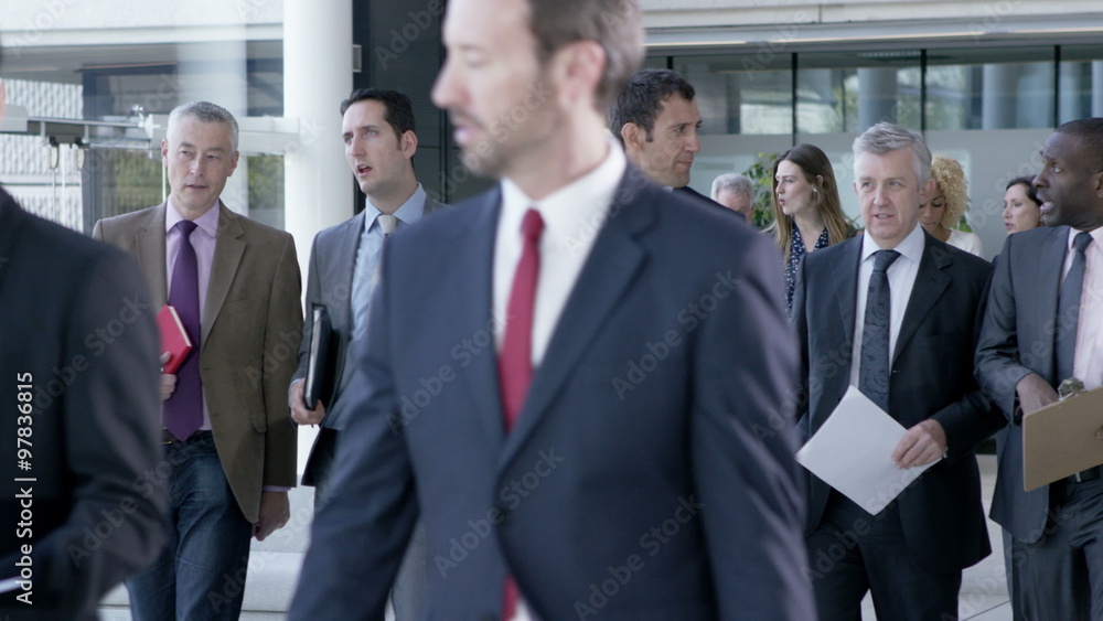 Large diverse business group talking as they walk through office building Large diverse business group talking as they walk through office building