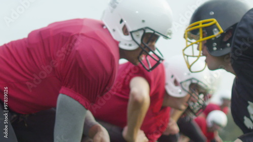 Opposing American football players crouched at line of scrimmage, ready to play