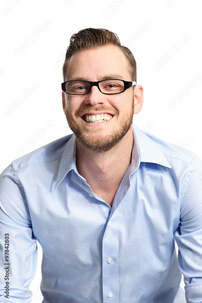 Smiling man wearing a blue shirt and glasses sitting down looking at camera. White background.