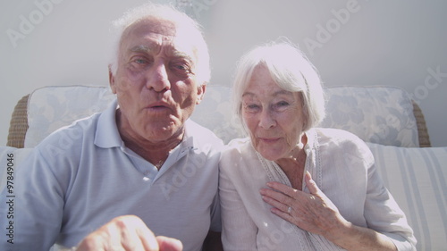 Cheerful senior couple having a skype conversation at home photo