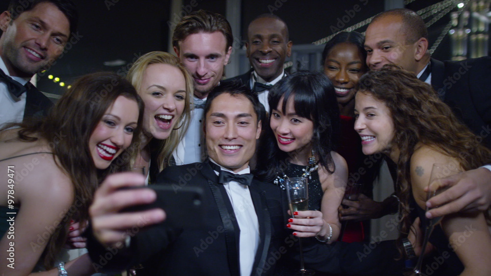 Happy attractive group of friends at a party pose to take a selfie together Happy attractive group of friends at a party pose to take a selfie together