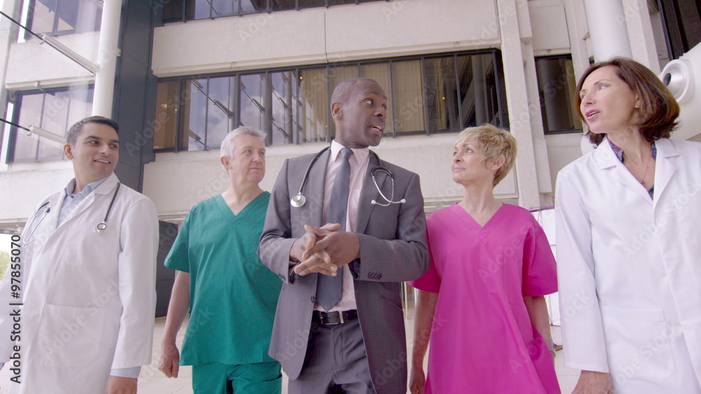 Mature group of medical professionals talking as they walk through hospital Mature group of medical professionals talking as they walk through hospital