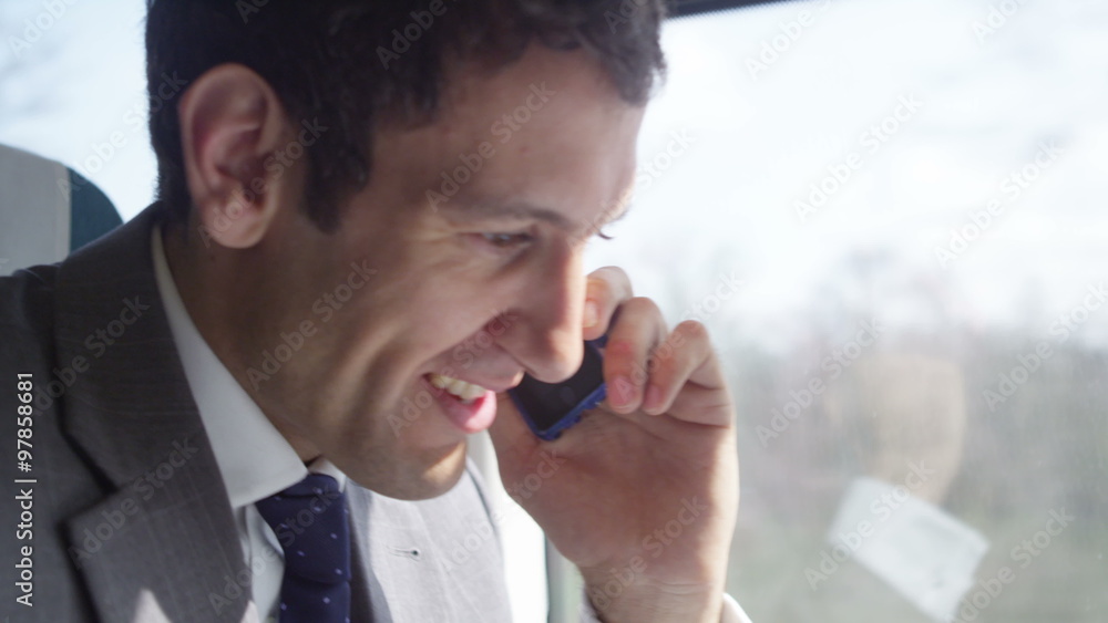 Attractive smiling businessman making mobile phone call on train journey. Shot on RED Epic. Attractive smiling businessman making mobile phone call on train journey. Shot on RED Epic.