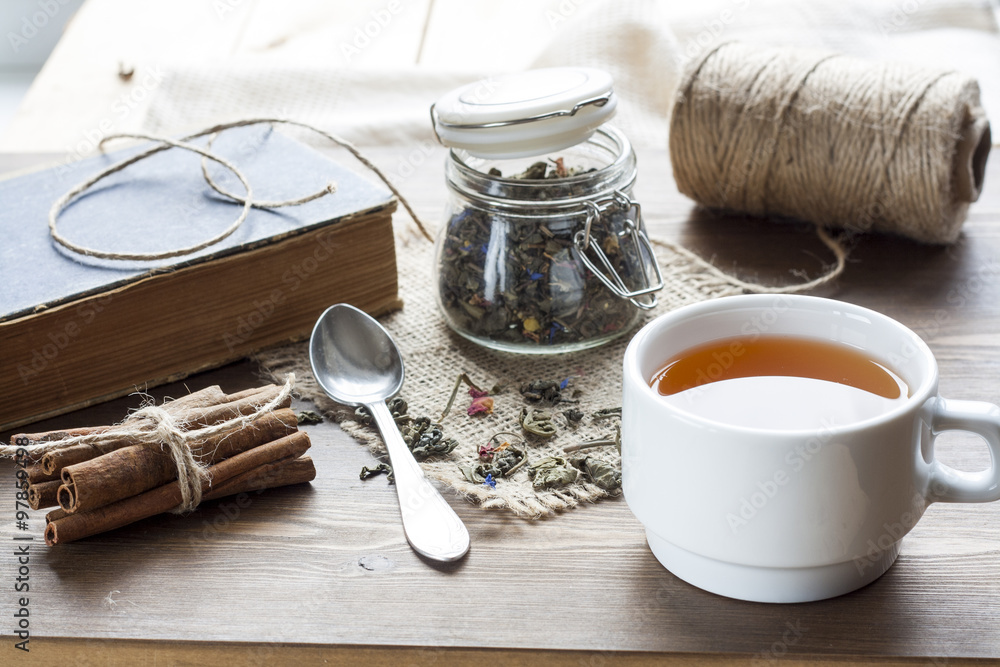 Cup of hot tea with books, tea leaves and flowers on wooden table. Vintage still life. Cup of hot tea with books, tea leaves and flowers on wooden table. Vintage still life.