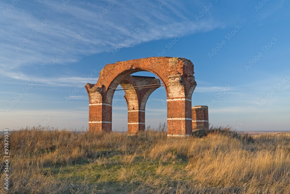 Brick arches of old church ruins solitary in the field. 
