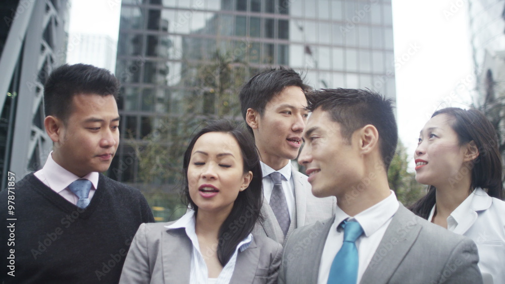 Young Asian business group all talking on mobile phones outdoors in the city Young Asian business group all talking on mobile phones outdoors in the city