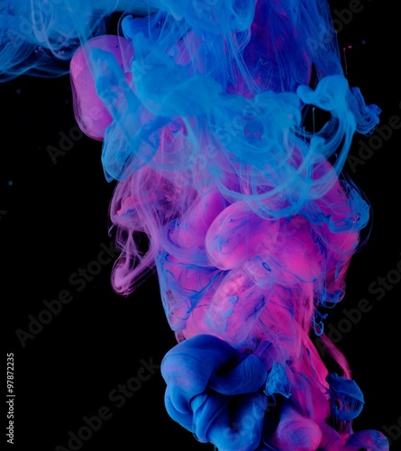 Blue pink clouds of ink in liquid isolated on black