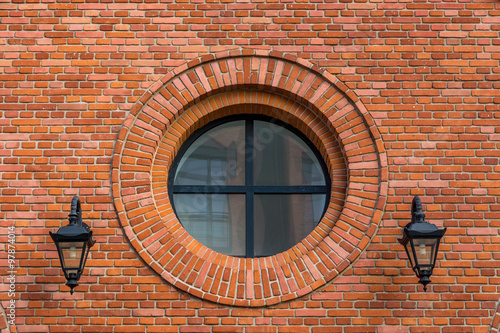 Beautifully renovated wall of an old textile factory with round window and two lanterns