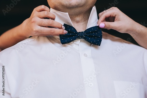 Man's hands touches bow-tie on a suit